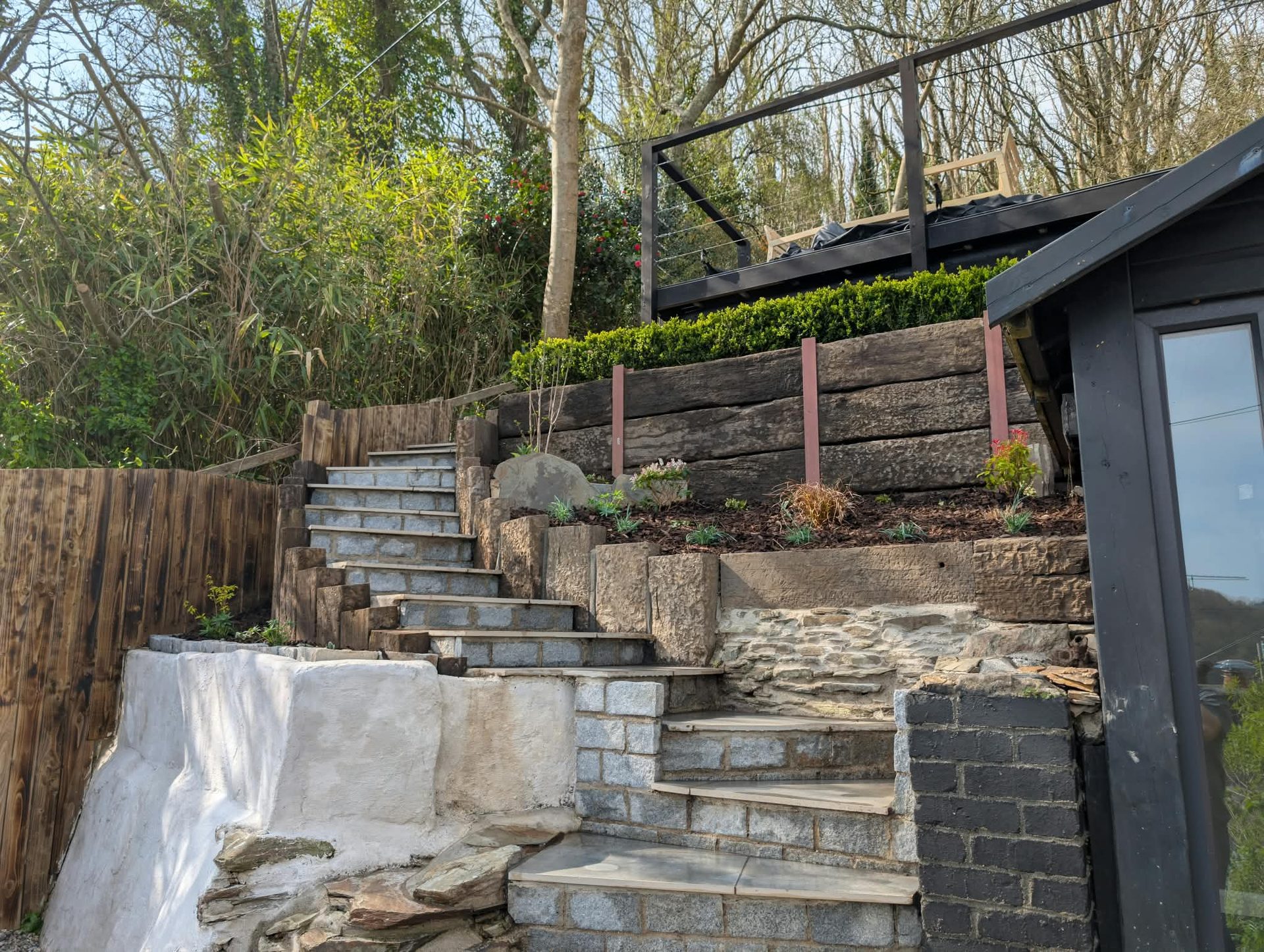 Tiered sleeper retaining beds with granite steps on a sloping Cornish garden