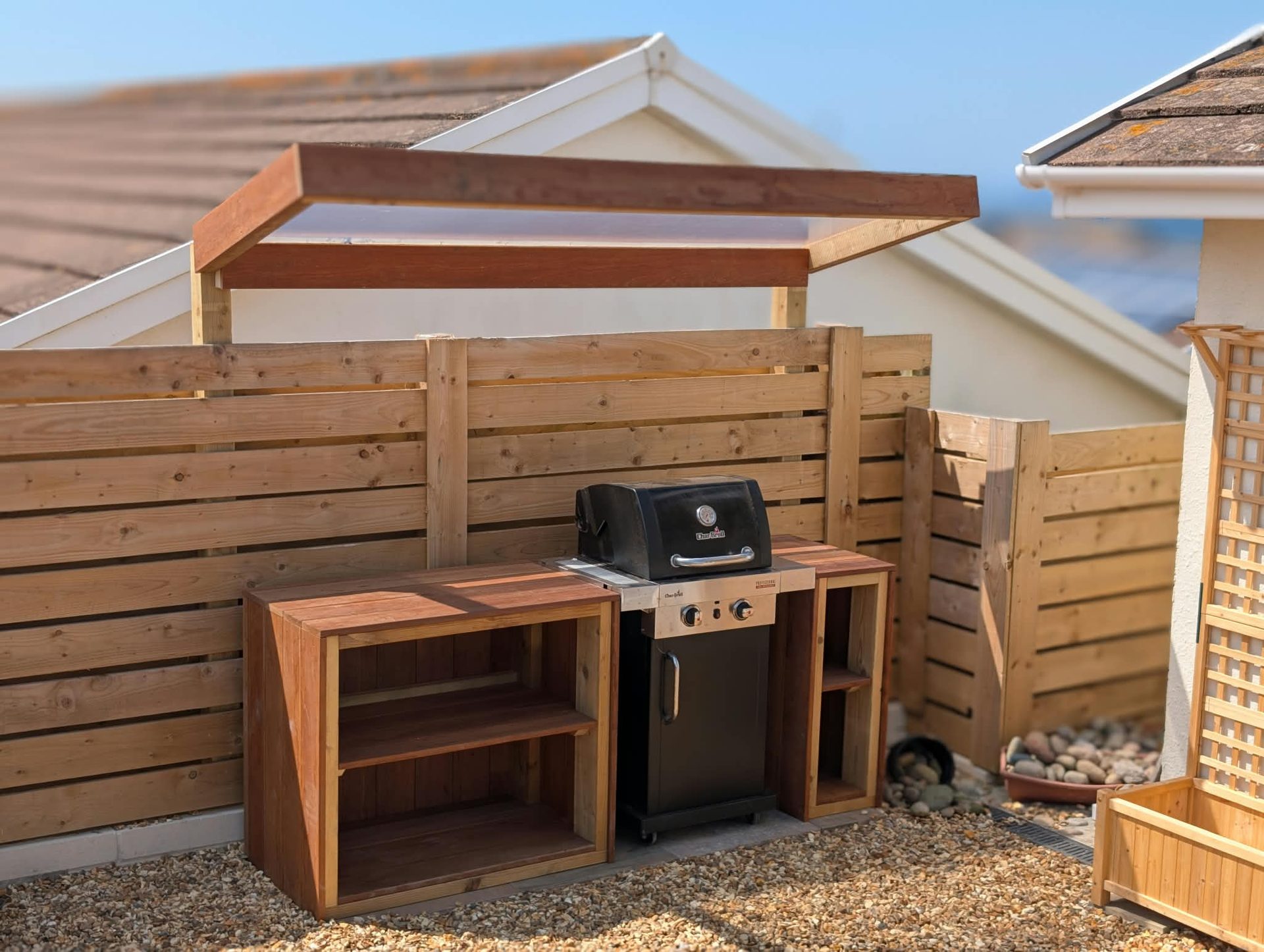 Outdoor kitchen with hardwood timber units and canopy in a Cornish garden