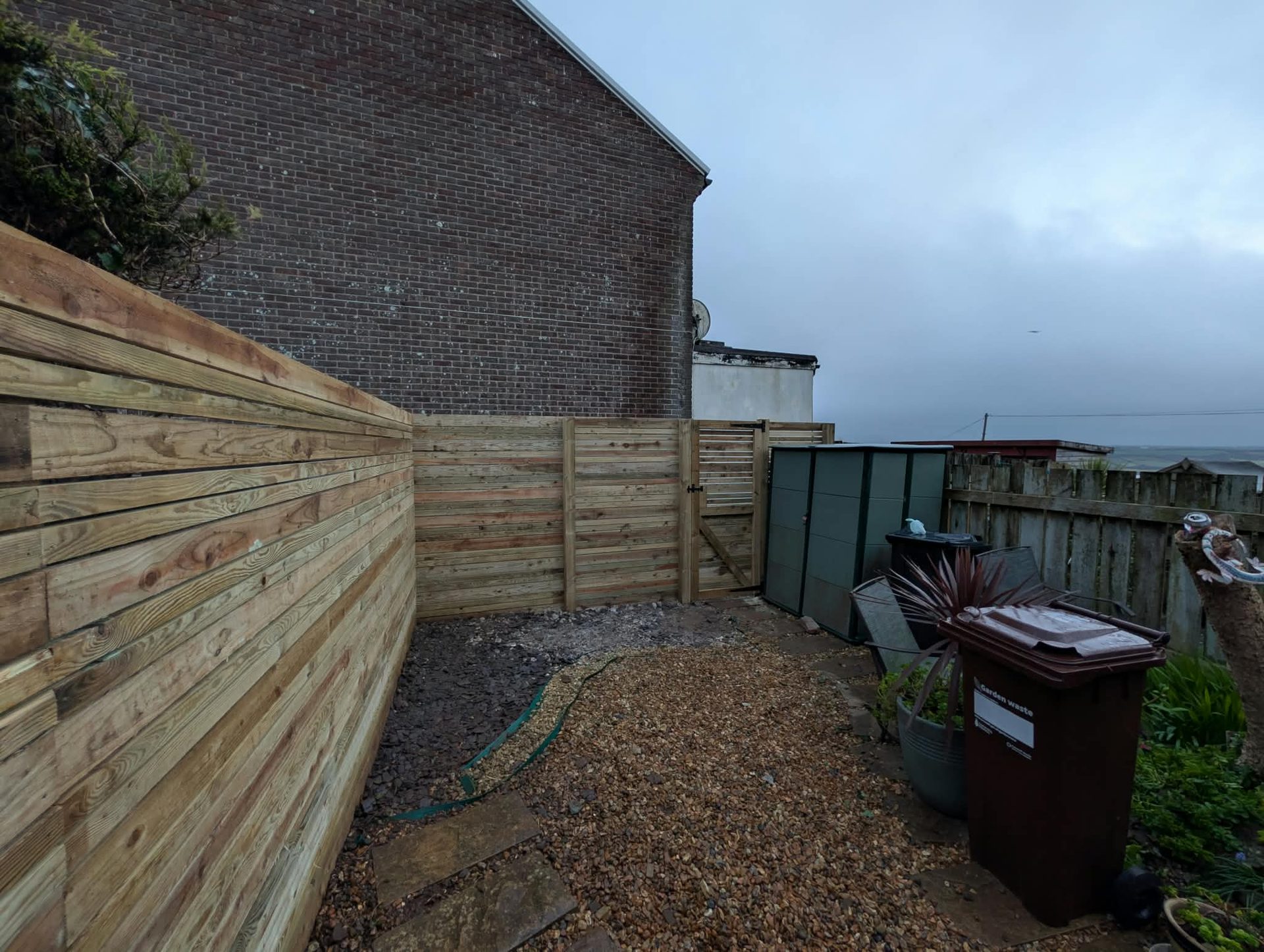 Horizontal slatted fence with matching side gate in a Cornish garden