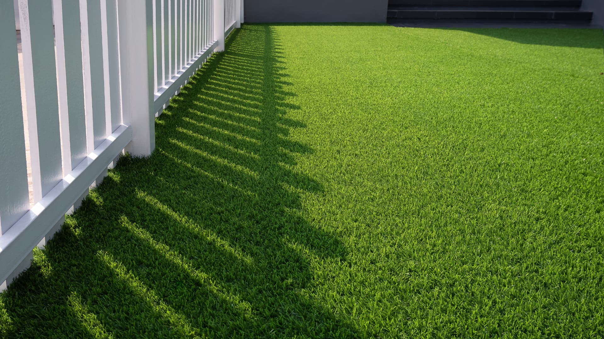 Artificial grass lawn beside a white picket fence