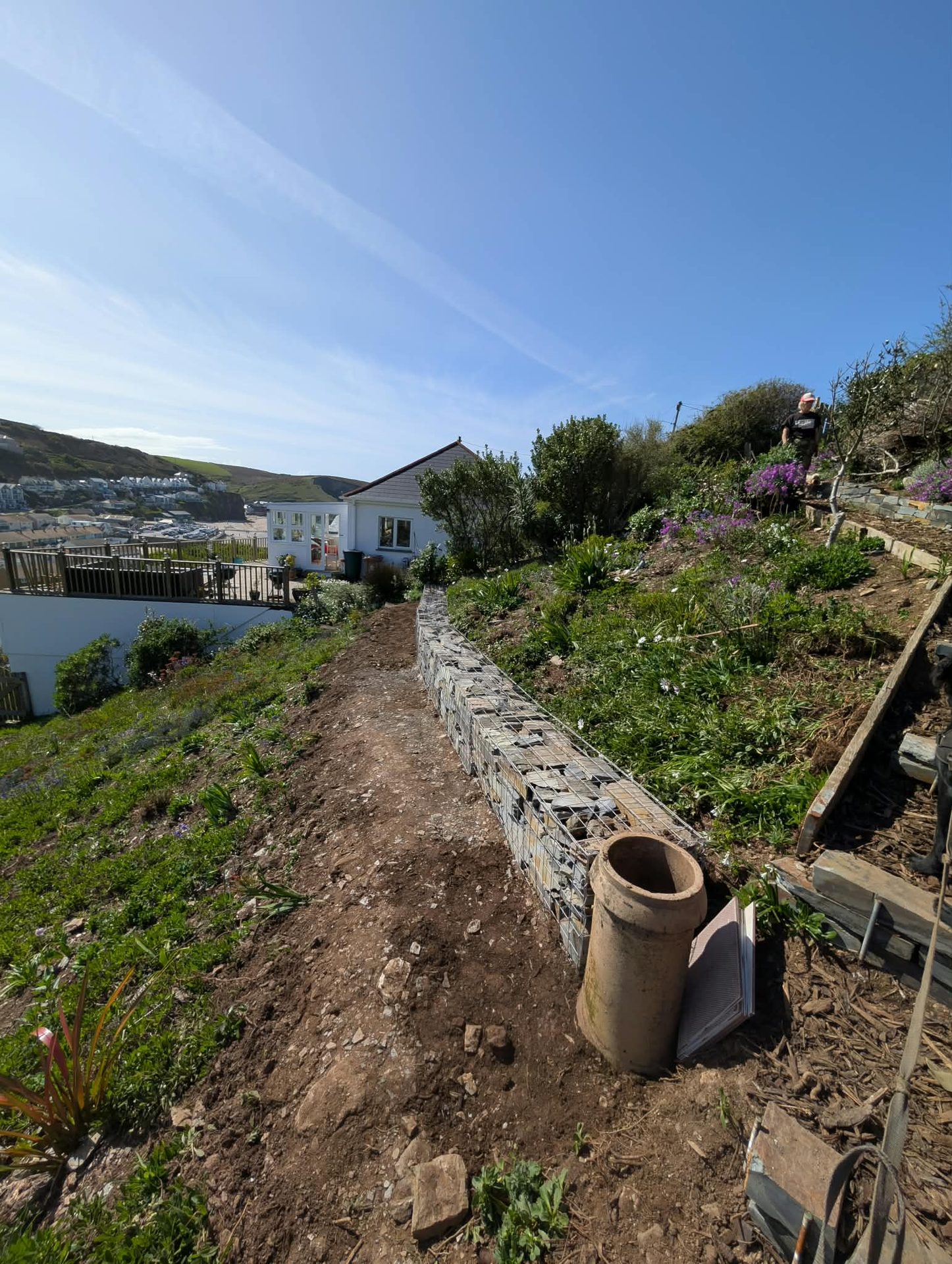 Gabion wall along a steep coastal slope above a Cornish town