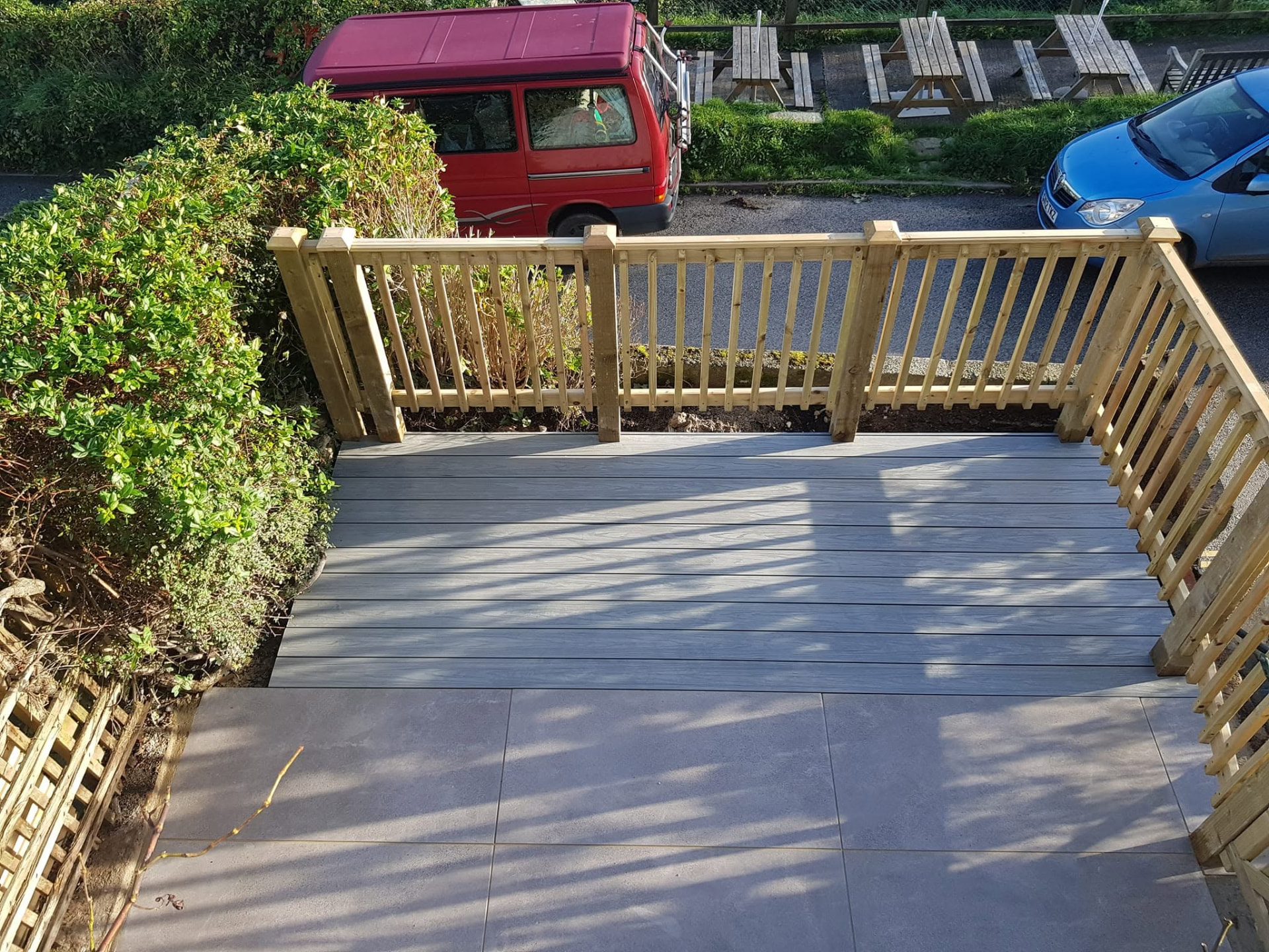 Grey composite decking with timber spindle balustrade and large-format paving in Cornwall