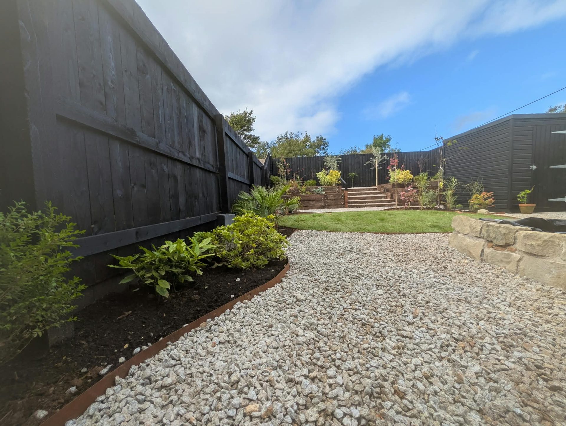 Curved gravel path with steel edging and planted border in a landscaped Cornish garden