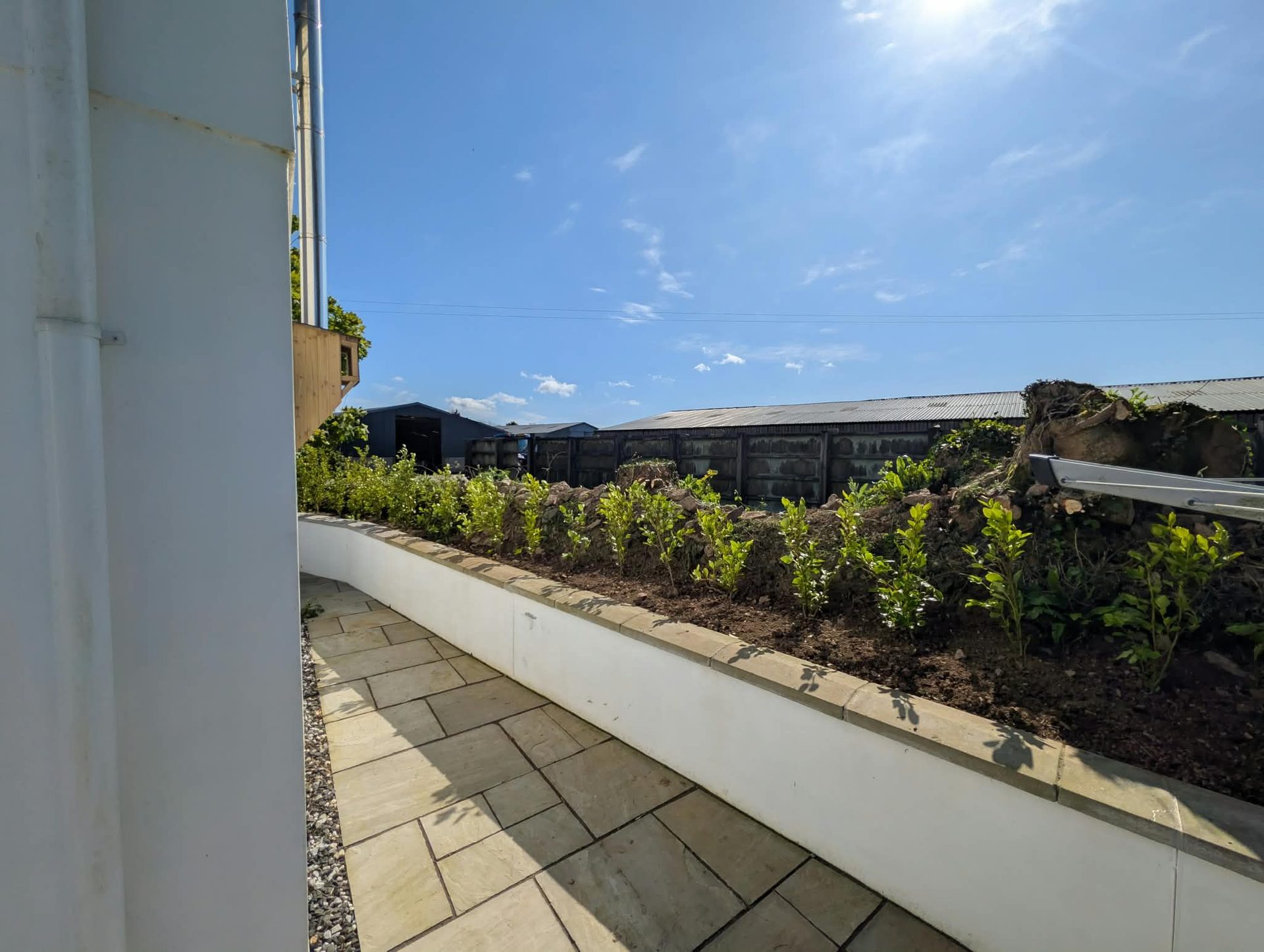 Sandstone paving path beside a rendered raised bed in a Cornwall garden